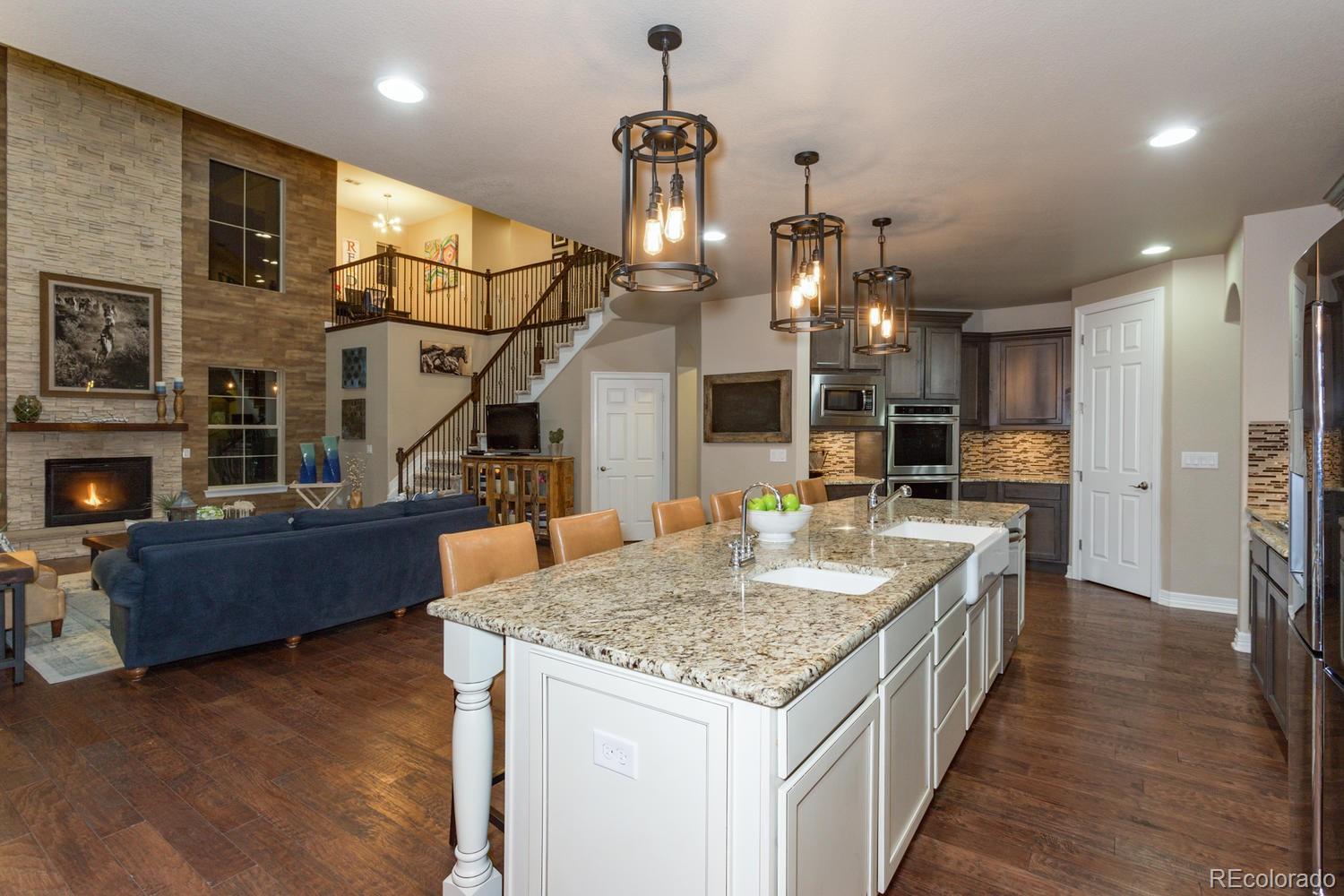 10808 Sundial Rim Road Highlands Ranch, CO 80126 - Photo 6 of 26 a kitchen with kitchen island granite countertop a stove and a wooden floors