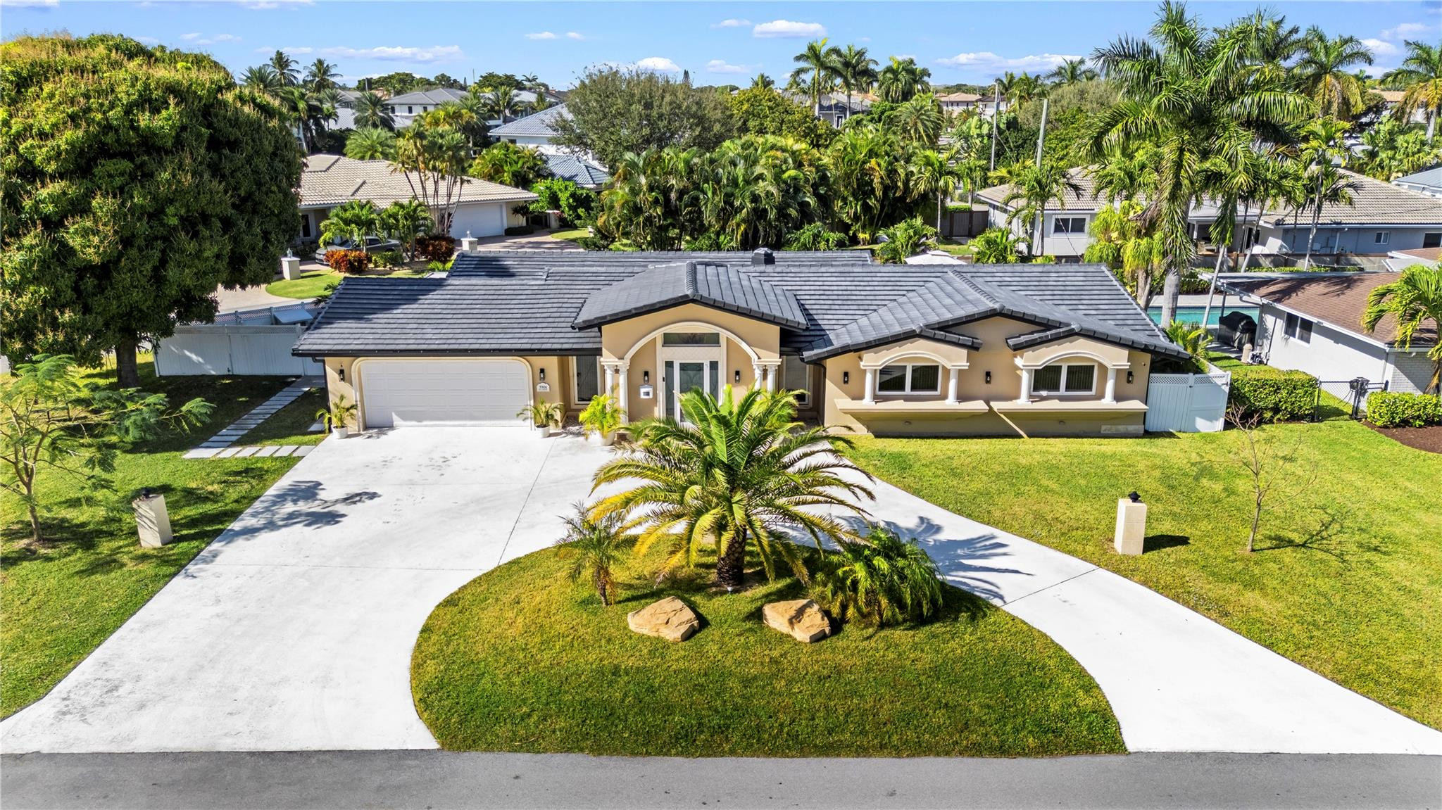 a view of a white house with a big yard plants and large trees
