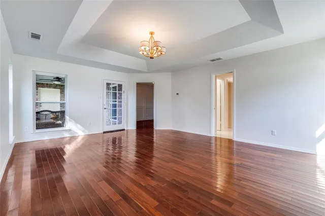 a view of an empty room with wooden floor and a large window