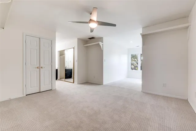 an empty room with closet and a chandelier fan