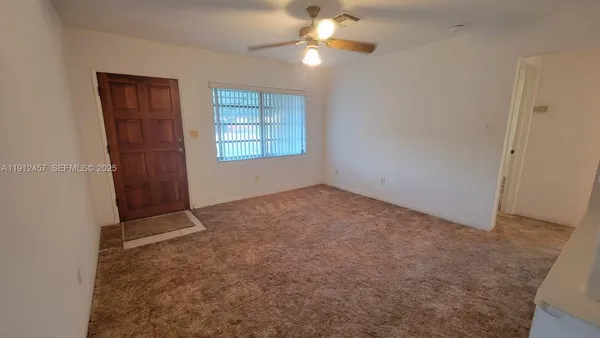 an empty room with windows and fan