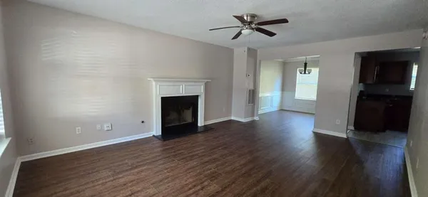 a view of an empty room with wooden floor and a fireplace