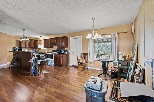 a kitchen with stainless steel appliances a stove a refrigerator a sink dishwasher and a dining table with wooden floor