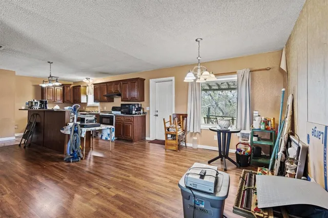 a kitchen with stainless steel appliances a stove a refrigerator a sink dishwasher and a dining table with wooden floor