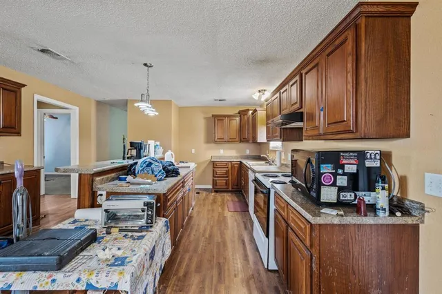 a kitchen with kitchen island granite countertop a sink stove and cabinets