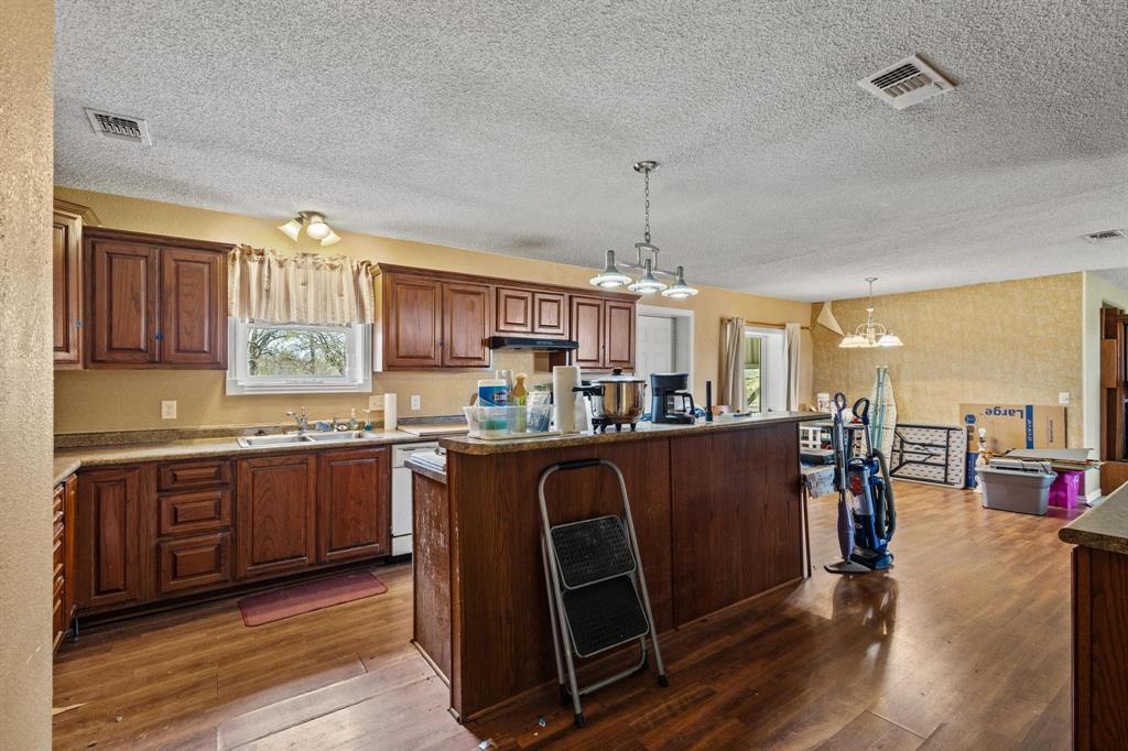 1841 County Road Honey Grove, TX 75446 - Photo 18 of 32 a kitchen with stainless steel appliances granite countertop a refrigerator a sink dishwasher a stove and a dining table with wooden floor