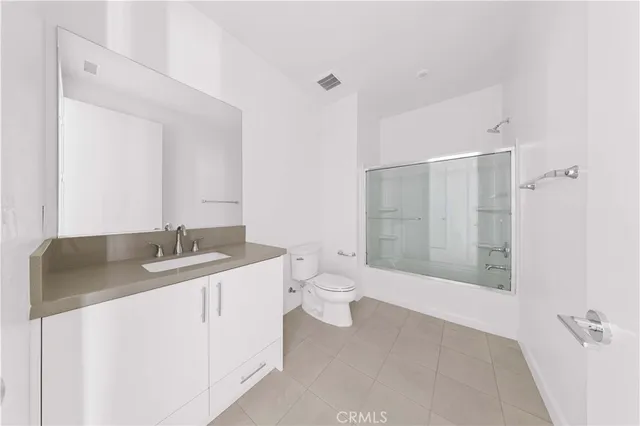 a bathroom with a granite countertop sink a toilet and shower