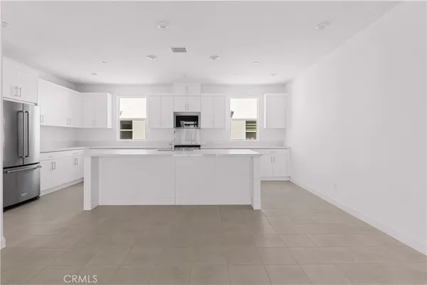 a large white kitchen with cabinets and a refrigerator