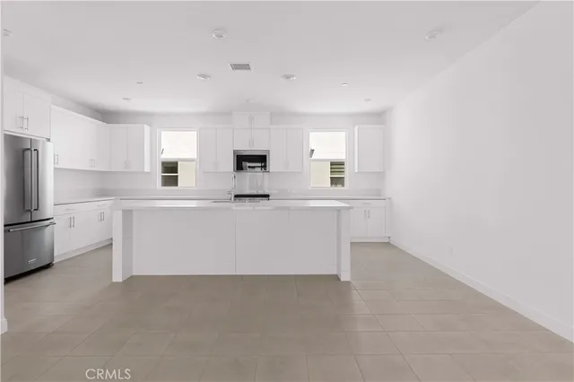 a large white kitchen with cabinets and a refrigerator