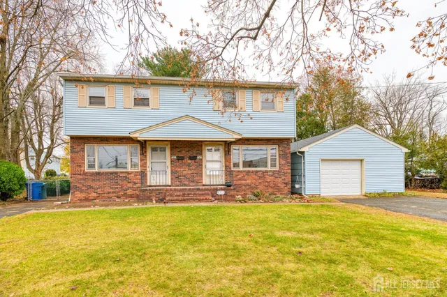 a front view of house with yard and trees in the background