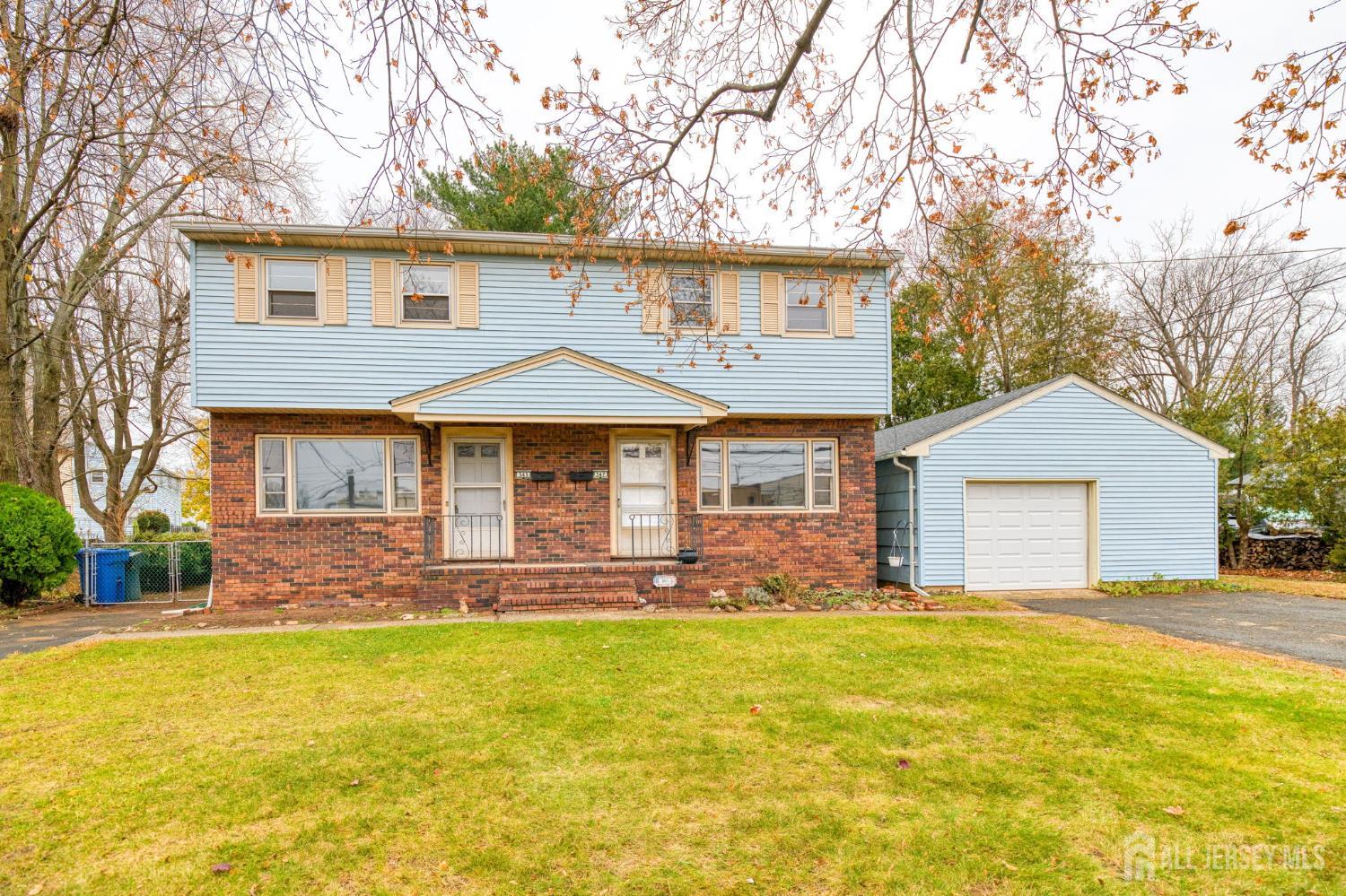 a front view of house with yard and trees in the background