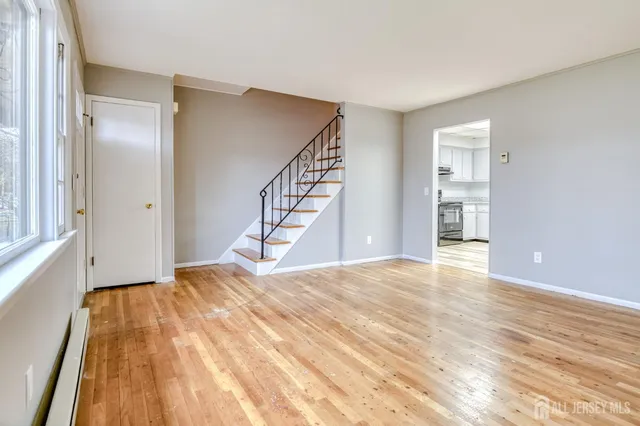 a view of an empty room with wooden floor and stairs