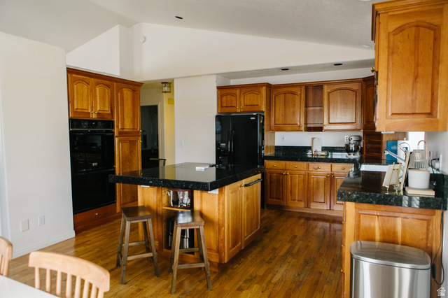 104 South Ridgeview Drive Orem, UT 84058 - Photo 14 of 49 Spacious kitchen featuring warm wood cabinetry, granite countertops, wood-finish flooring, a built-in double oven, and a central island with seating