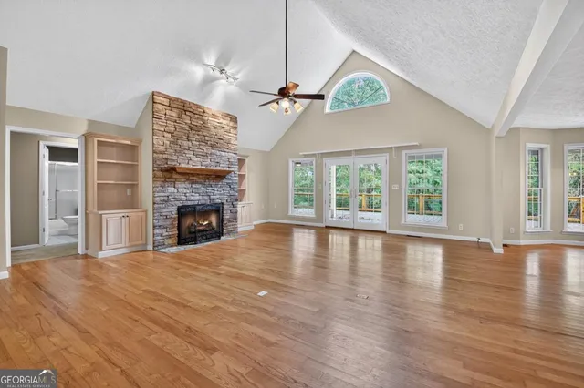 an empty room with windows fireplace and wooden floor