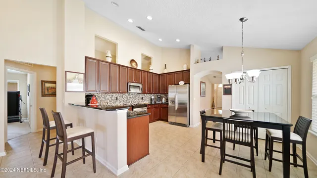 a kitchen with stainless steel appliances kitchen island granite countertop a table chairs and a refrigerator