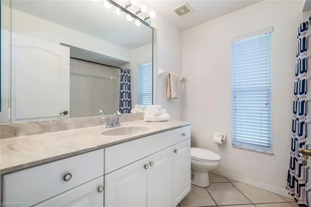 a bathroom with a granite countertop toilet sink and mirror
