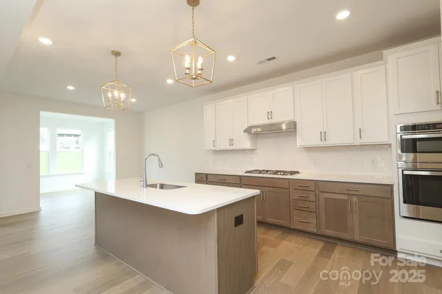 a kitchen with kitchen island granite countertop a sink cabinets and stainless steel appliances