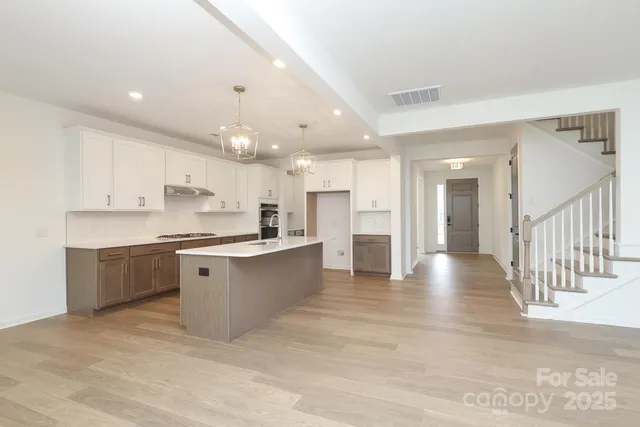 a large kitchen with kitchen island a sink a stove a refrigerator and a dining table with wooden floor