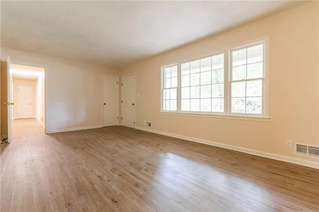 an empty room with wooden floor and windows