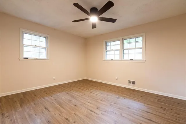 an empty room with wooden floor and windows