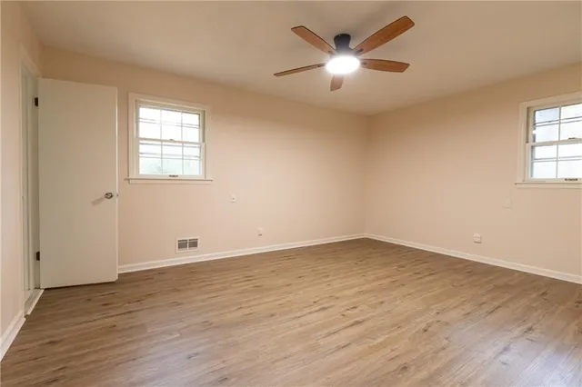 an empty room with wooden floor and windows