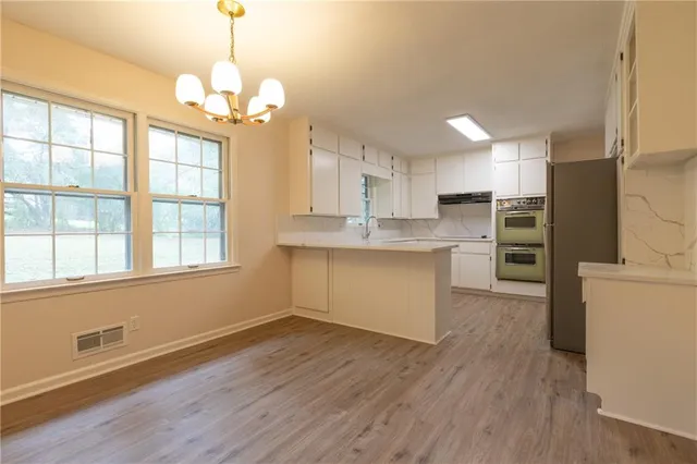 a kitchen with stainless steel appliances granite countertop a refrigerator a sink dishwasher a stove and white countertops with wooden floor