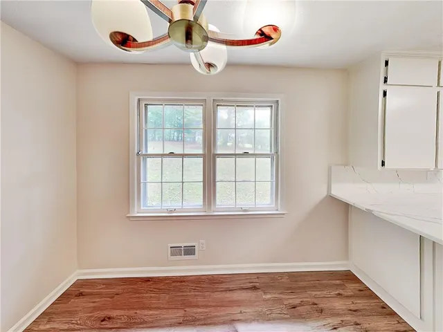 a view of an empty room with a window and wooden floor