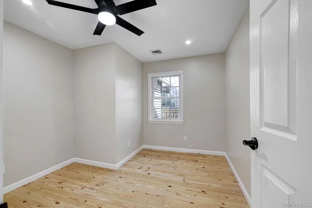 an empty room with wooden floor fan and windows