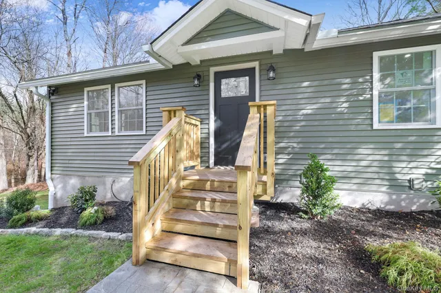 a view of wooden house with a yard and stairs