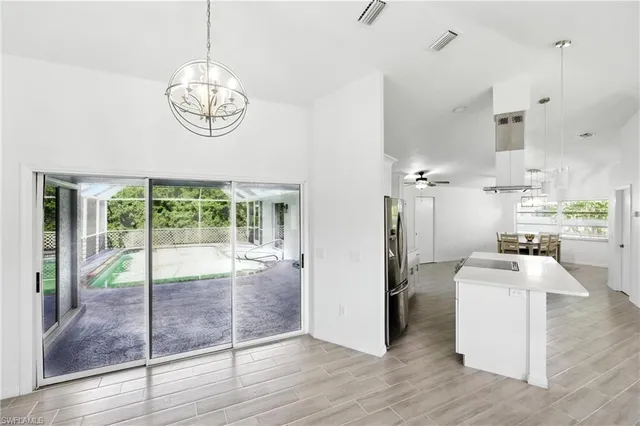 a view of a dining room and livingroom with furniture wooden floor a rug a fireplace and a chandelier