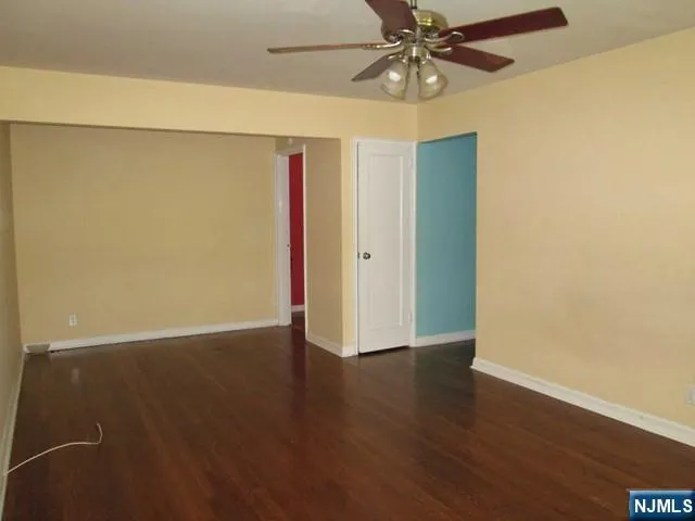 an empty room with wooden floor and fan