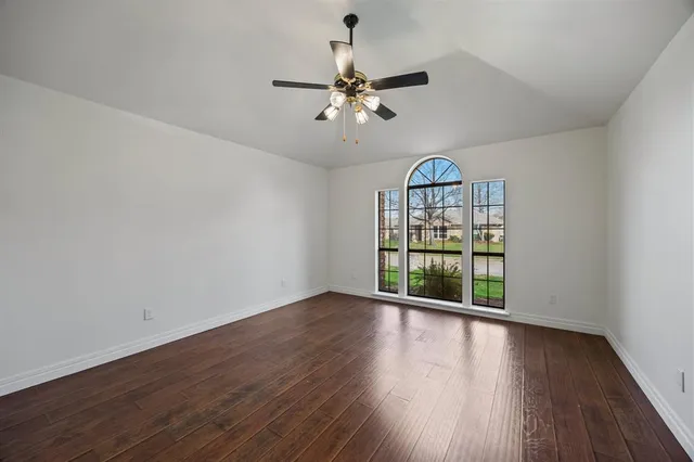 a view of a room with wooden floor chandelier a ceiling fan and windows