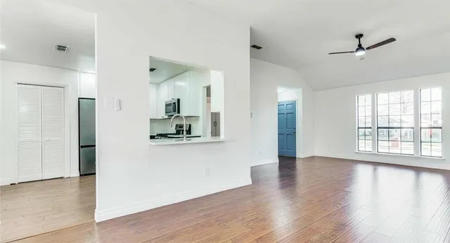 a view of empty room with wooden floor and fan