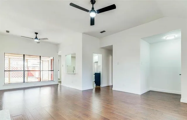 a view of an empty room with a window and wooden floor