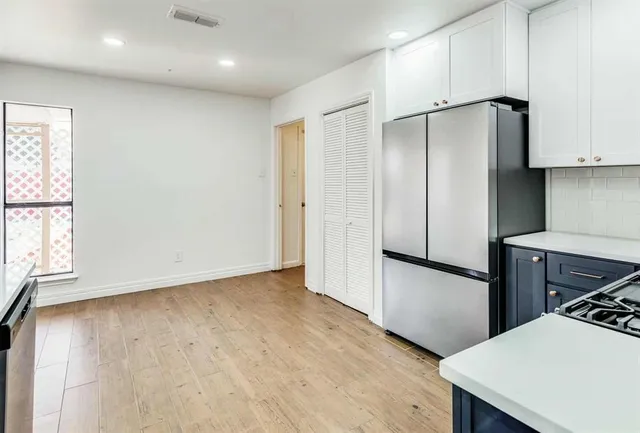 a view of a kitchen with a fridge and wooden floor