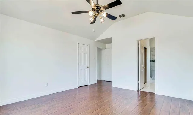 an empty room with wooden floor chandelier fan and closet area