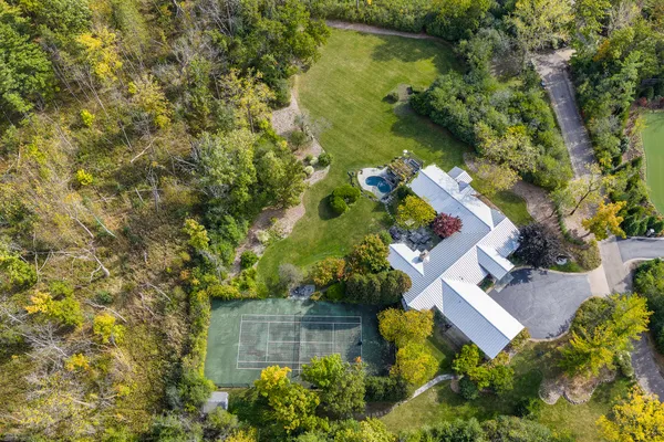 an aerial view of residential house with outdoor space and trees all around