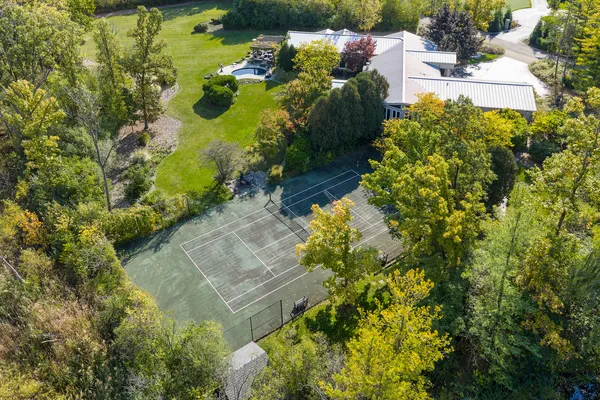 an aerial view of residential house with outdoor space and trees all around