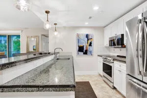 a large kitchen with stainless steel appliances granite countertop a stove a sink and a refrigerator