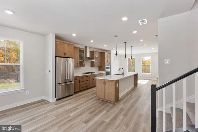a large kitchen with a center island wooden floor stainless steel appliances and windows