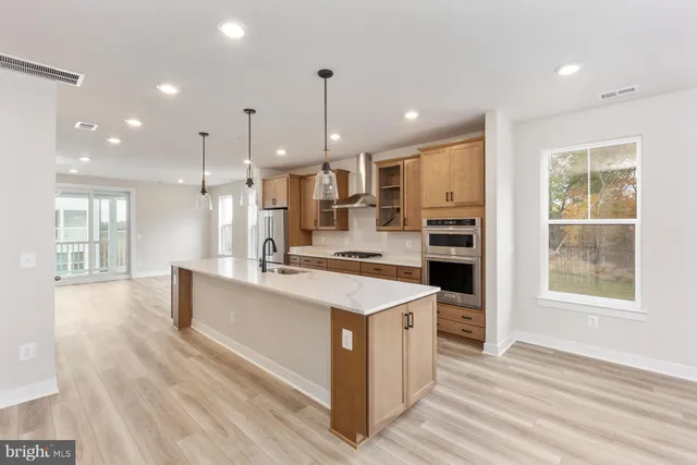 a large kitchen with kitchen island a stove a sink a refrigerator and a dining table with wooden floor