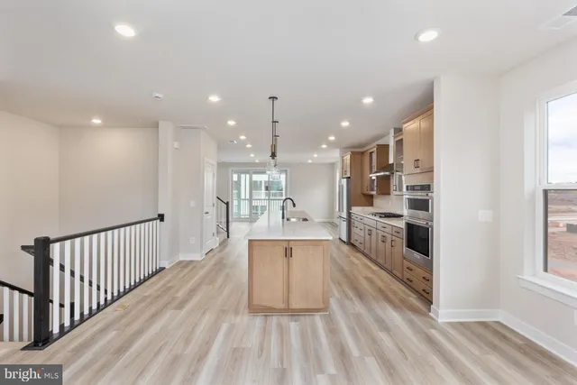 a view of a kitchen with kitchen island granite countertop wooden floor stainless steel appliances and windows