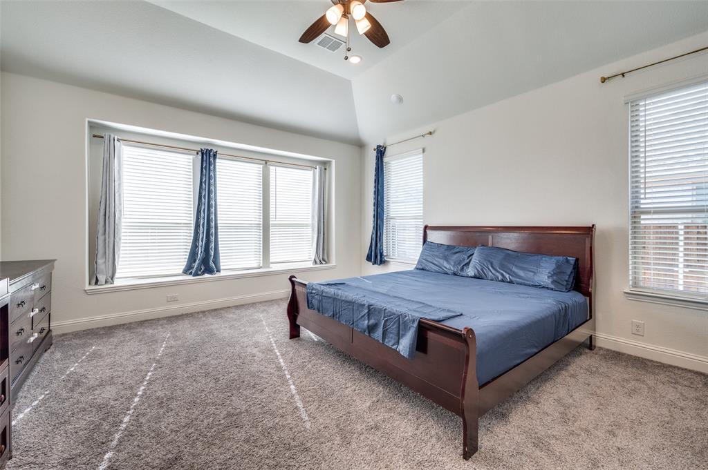 1616 George Lane Little Elm, TX 75068 - Photo 10 of 28 a spacious bedroom with a large bed and a chandelier fan