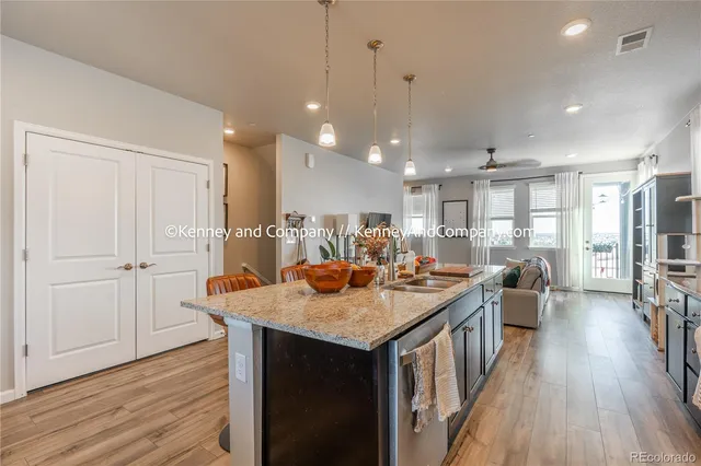 a kitchen with stainless steel appliances granite countertop a refrigerator a sink dishwasher a stove and white cabinets with wooden floor