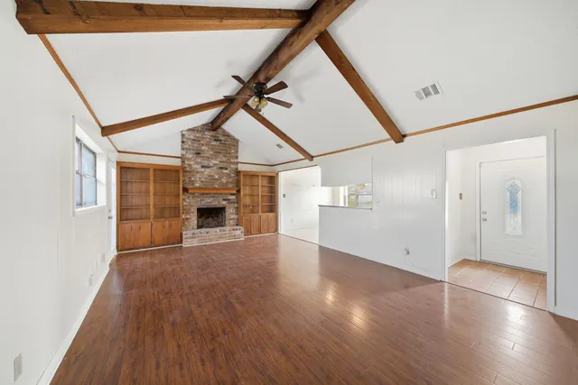a view of empty room with wooden floor and fireplace