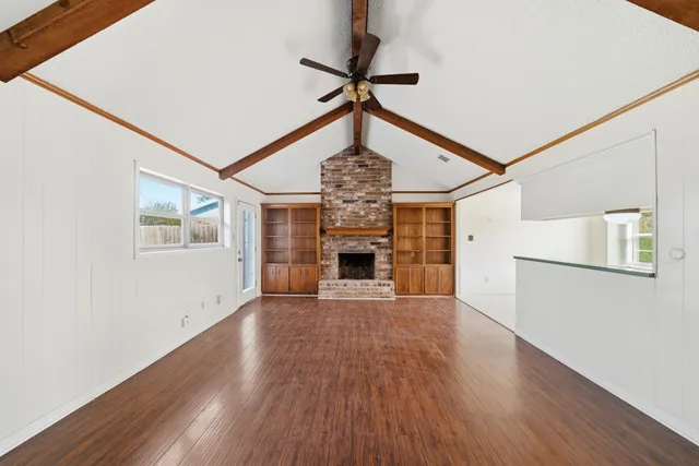 a view of a livingroom with wooden floor a ceiling fan and windows