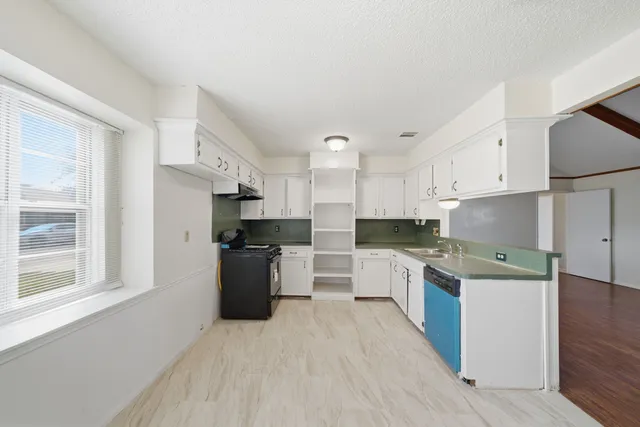 a kitchen with stainless steel appliances granite countertop a stove top oven a sink dishwasher and a refrigerator with wooden floor