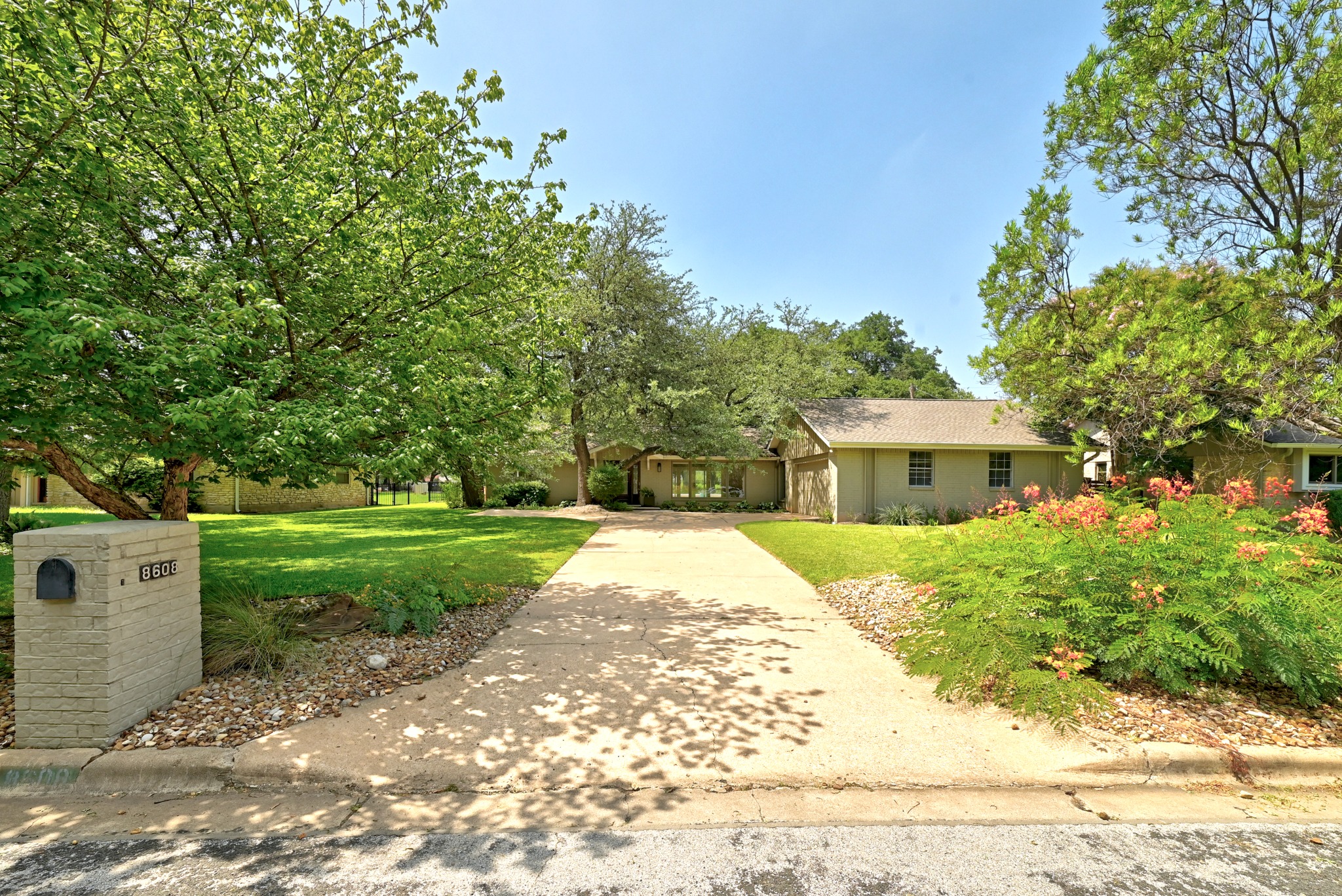 8608 Crest Ridge Circle Austin, TX 78750 - Photo 4 of 38 A long driveway leads to a welcoming home framed by lush greenery and vibrant landscaping.