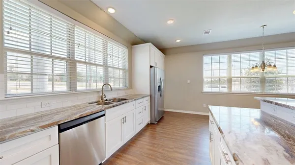 a large kitchen with granite countertop a large window sink and cabinets