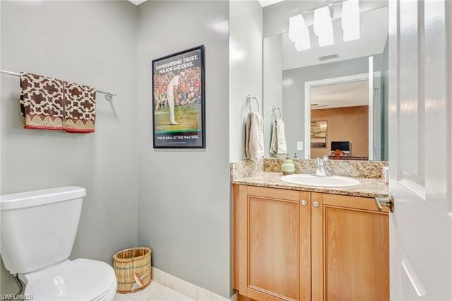 a bathroom with a granite countertop toilet a sink and a mirror